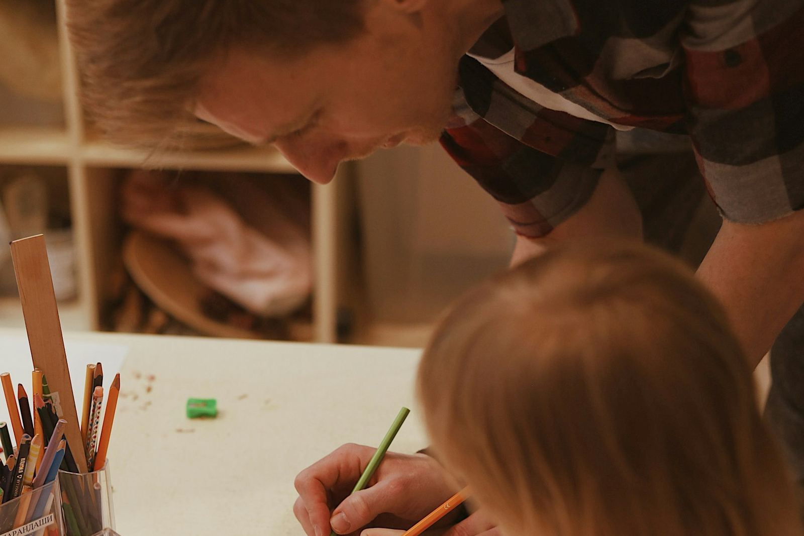 Pappa och barn ritar tillsammans vid köksbordet